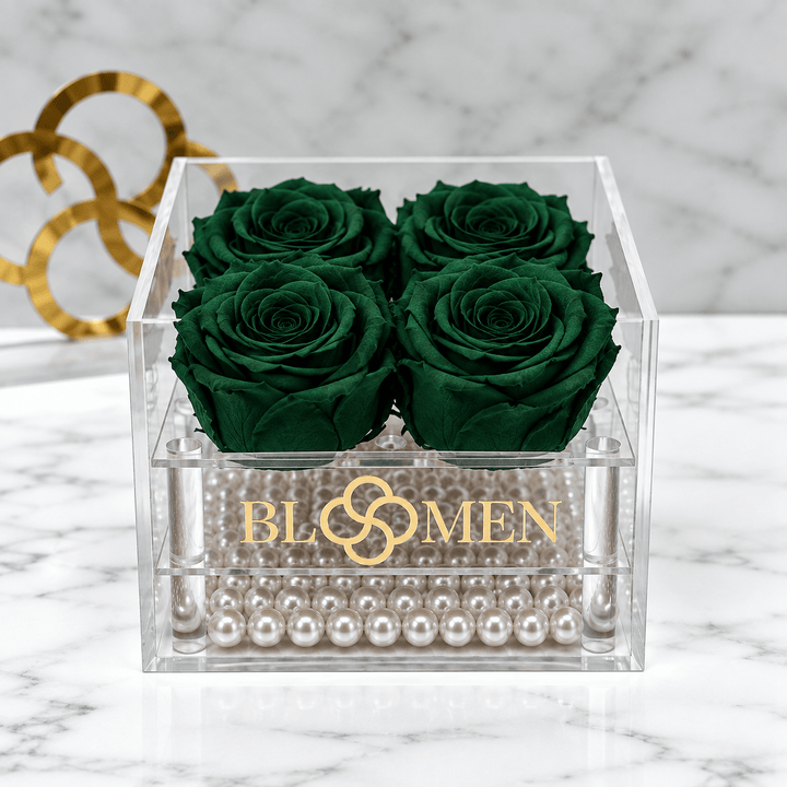 Top view of four hunter green everlasting roses in a clear box