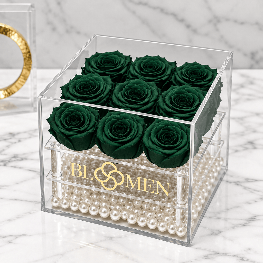 Nine hunter green everlasting roses in a clear Bloomen box with decorative beads, angled view