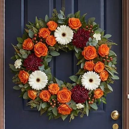 Fall door wreath with orange roses, white gerberas and burgundy chrysanthemums, close-up on a navy front door